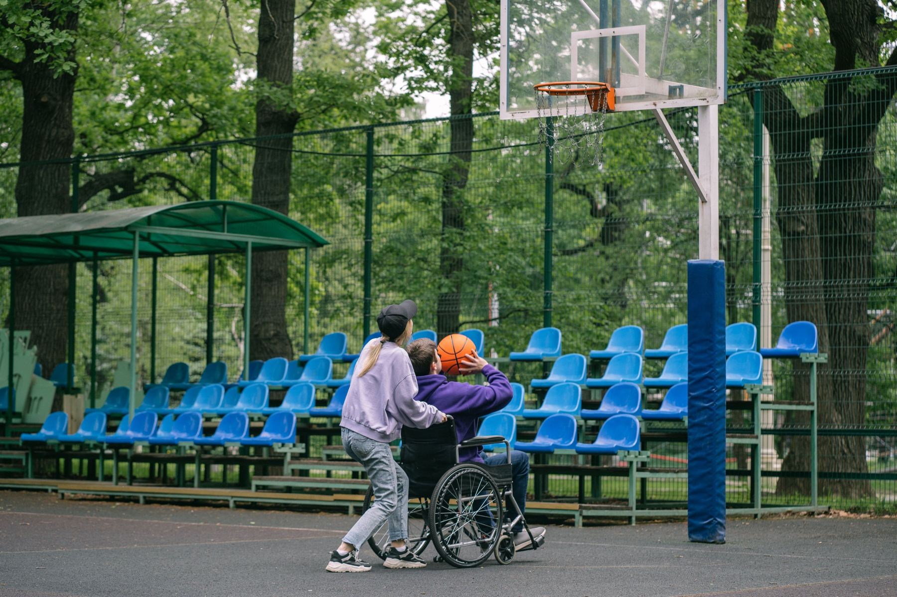 A support worker laughing with a man in a wheelchair outdoors